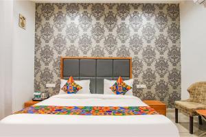 a bedroom with a large bed and a chair at Hotel Royal Maple in Ludhiana