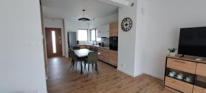 a kitchen and dining room with a table and a clock at Garden Baltic II in Trzęsacz