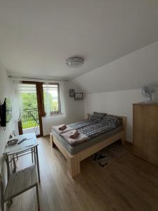 a bedroom with a bed and a table and a window at APARTAMENT RYBICAL nad jeziorem in Ryn