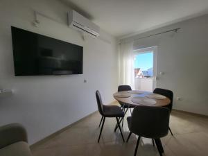 Un comedor con mesa y sillas y un televisor. en Mila Apartments Zadar, en Zadar