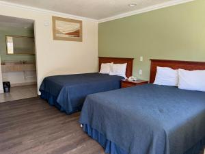 a hotel room with two beds and a bathroom at Regency Inn Fresno in Fresno