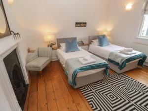 a room with two beds and a chair and a fireplace at Scillonia in Penzance