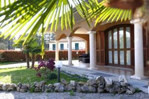 a house with a palm tree and a porch at Villa con giardino in Pontecurone