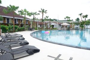 a pool at a resort with lounge chairs and palm trees at Ataya Hotel in Adi Sumarmo Wiryokusumo