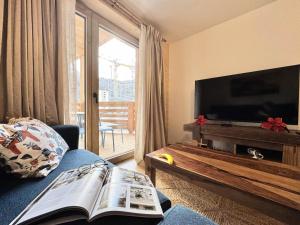 a living room with a tv and a book on a couch at Résidence Le Living Stone B - LIVING STONE B MAE-1781 in Vars +8 photos