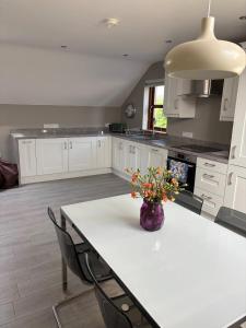 a kitchen with a table with a vase of flowers on it at Modern Country Loft, Ballymena in Teeshan +15 photos