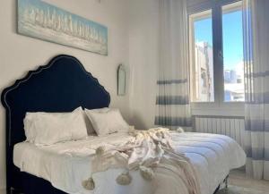 a bedroom with a bed with a blue headboard and a window at The sea view in Douar el Hafey