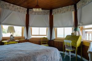 a bedroom with a bed and two chairs and windows at The 8th Maine Regiment Lodge and Museum in Peaks Island