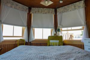 a bedroom with a bed and two windows with white curtains at The 8th Maine Regiment Lodge and Museum in Peaks Island
