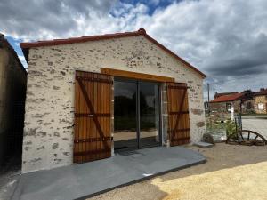 a small white building with wooden doors on it at Gîtes La Pagaille in Bournezeau