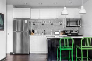 a kitchen with green chairs and a stainless steel refrigerator at Sleeps 8 4 SoBro Suites w Kitchens Art Walk to Broadway – by AvantStay in Nashville +12 photos