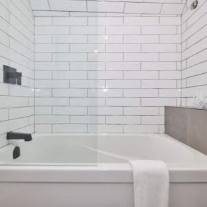 a white bathroom with a bath tub with a towel at Riverside Stay in Niagara Falls