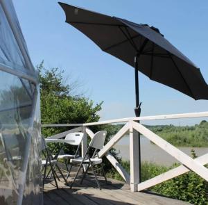 a couple of chairs and an umbrella on a deck at Глемпінг Еко-сфера in Dubovtsy