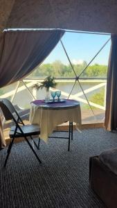 a table and chairs in a room with a large window at Глемпінг Еко-сфера in Dubovtsy