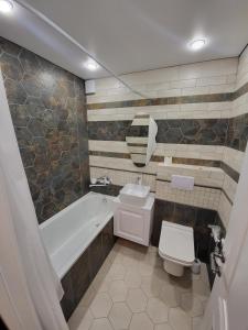 a bathroom with a tub and a toilet and a sink at Апартаменты 2 in Karagandy