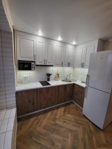 a kitchen with white cabinets and a white refrigerator at Апартаменты 2 in Karagandy