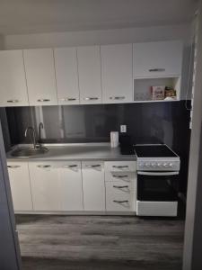kuchnia z białymi szafkami i kuchenką w obiekcie Sarajevo apartman w Sarajewie