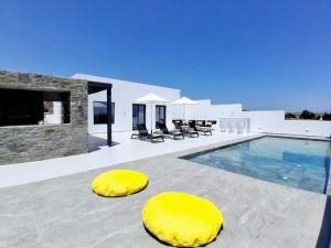 a villa with a swimming pool with yellow ottomans at GBR 1 - Golden Beach Residences in Chrissi Akti