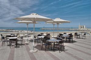 - un groupe de tables et de chaises avec parasols sur une plage dans l'établissement Hotel Stella Marina, à San Vincenzo