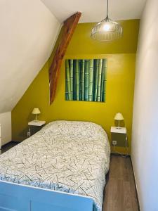 1 dormitorio con 1 cama con paredes amarillas y 2 lámparas en Gravelines Beach Apartment, en Gravelines