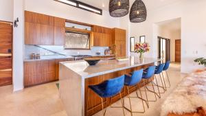 a kitchen with a large island with blue bar stools at Villa Damiana by The Agency Baja in El Pescadero