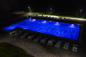 a swimming pool with chairs around it at night at Hotel Helikon in Yanoshi