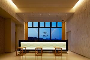 a lobby with two stools and a large window at Candeo Hotels Matsuyama Okaido in Matsuyama