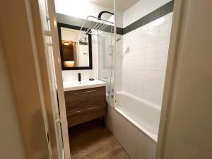 a bathroom with a sink and a tub and a mirror at Appartement lumineux avec balcon et parking in La Plagne Tarentaise