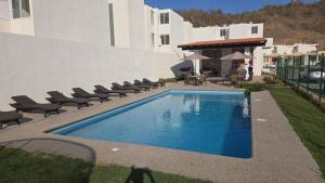 a swimming pool with chairs next to a building at Departamento Belinda in Ixtapa