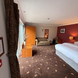 a hotel room with a bed and a couch at Plas Derwen Hotel in Abergavenny