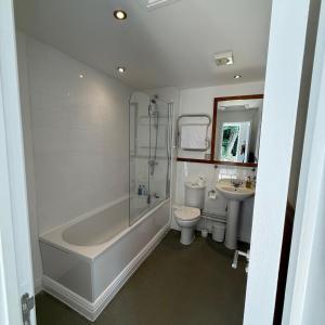 a bathroom with a tub and a toilet and a sink at Plas Derwen Hotel in Abergavenny +23 photos
