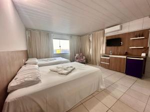 ein Hotelzimmer mit zwei Betten und einem Fernseher in der Unterkunft Juscelino Pousada lazer in Tibau