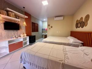 ein Schlafzimmer mit zwei Betten und einem Flachbildfernseher in der Unterkunft Juscelino Pousada lazer in Tibau + 4 Fotos