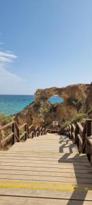 a wooden boardwalk leading to the beach with a blue umbrella at Algarve Dream Escape in Armação de Pêra