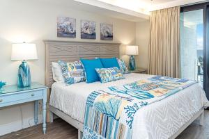 a bedroom with a bed with blue pillows and a window at The all-new Summer House on Romar Beach-gulf front in Orange Beach +43 photos