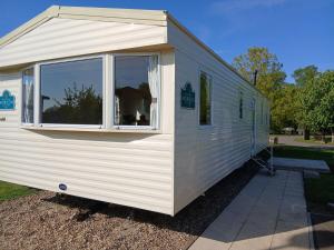 a white trailer with a window and a dog in it at Lexi's Lodge in Tattershall