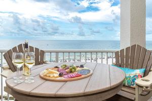 a table with a plate of food and wine glasses on the beach at The all-new Summer House on Romar Beach-gulf front in Orange Beach