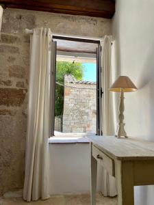 una finestra in una stanza con una scrivania e un tavolo con una lampada di Le Logis de la Bastide a Lauzerte