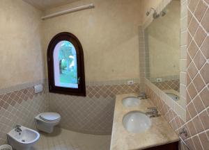 a bathroom with two sinks and a toilet and a window at Le Palme Luxury Costa Smeralda in Arzachena +7 photos
