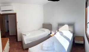 two beds in a small room with white sheets at Le Palme Luxury Costa Smeralda in Arzachena