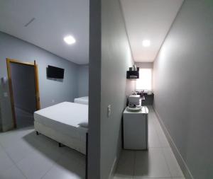 a bedroom with a white bed and a small table at Vila Dumont no Centro de Foz in Foz do Iguaçu