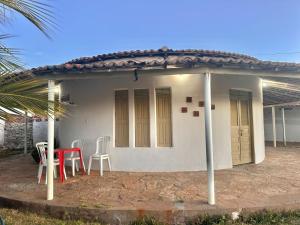 ein kleines weißes Haus mit einem roten Tisch und Stühlen in der Unterkunft Juscelino Pousada lazer in Tibau