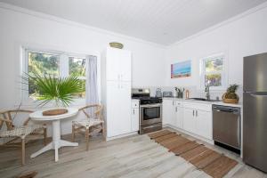 a kitchen with white cabinets and a table with a plant at Bica Bung - New! Private Beachfront Cottage French Leave Beach bungalow in Colebrooke Dale