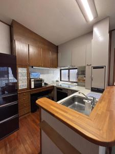 a large kitchen with wooden cabinets and a sink at 沖縄やどや in Nago