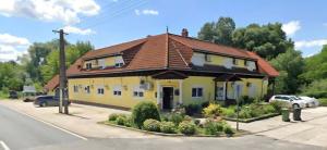 a yellow house with a brown roof on a street at Malom Fogadó in Balatonboglár