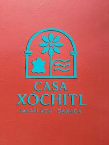a sign on a red wall with a casa kotu logo at Casa Xochitl in Oaxaca City +18 photos