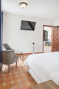 a bedroom with a bed and a chair and a mirror at Casa Xochitl in Oaxaca City