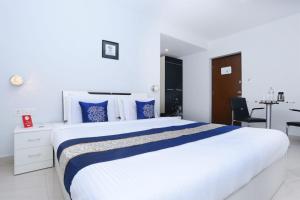 a bedroom with a large white bed with blue pillows at Super Townhouse Malabar Illam Kochi in Cochin