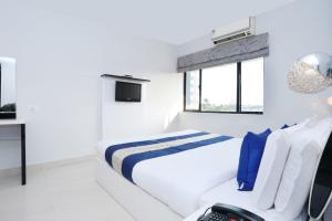 a white bedroom with a bed and a window at Super Townhouse Malabar Illam Kochi in Cochin
