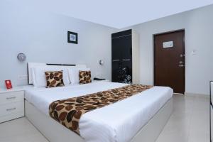 a white bedroom with a large bed with leopard pillows at Super Townhouse Malabar Illam Kochi in Cochin